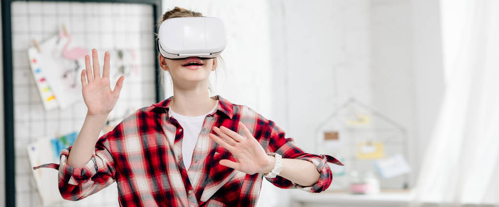 Panoramische shot van tiener in geruite shirt en VR headset - Foto, afbeelding