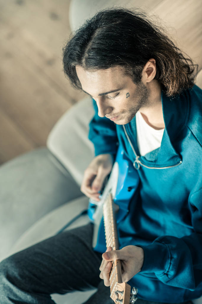 Doordachte knappe gitarist zijn muziekinstrument spelen - Foto, afbeelding