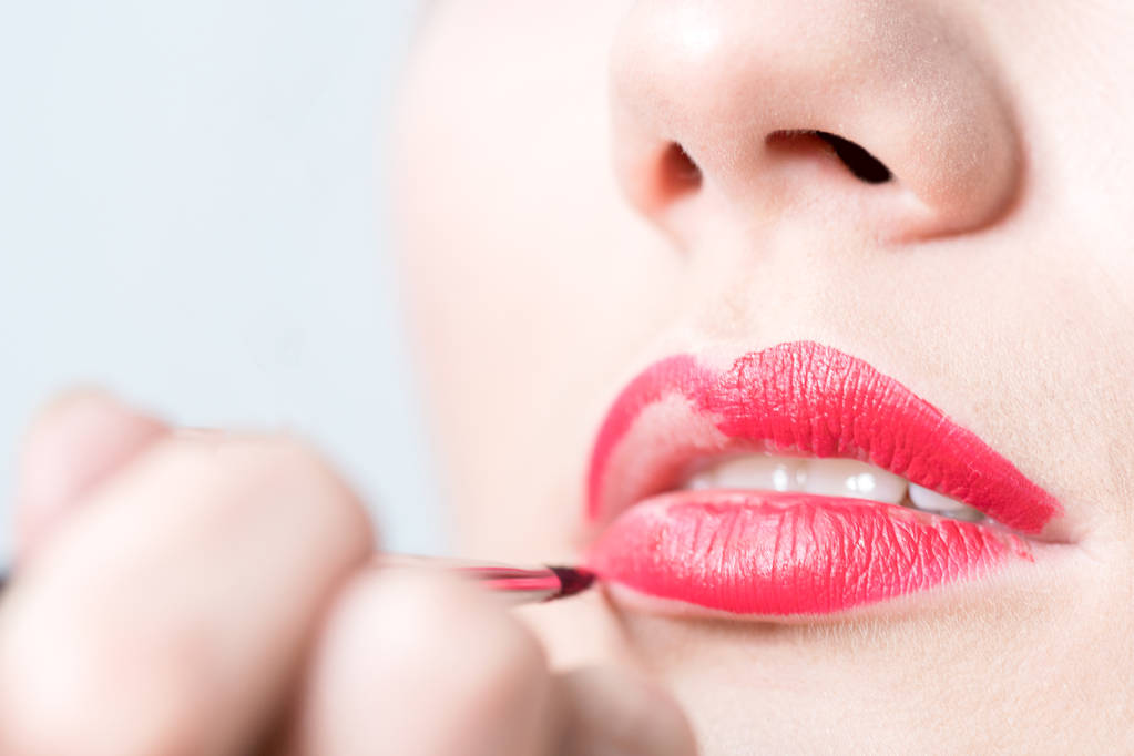 Close-up van meisje verven lippen met rode lippenstift - Foto, afbeelding