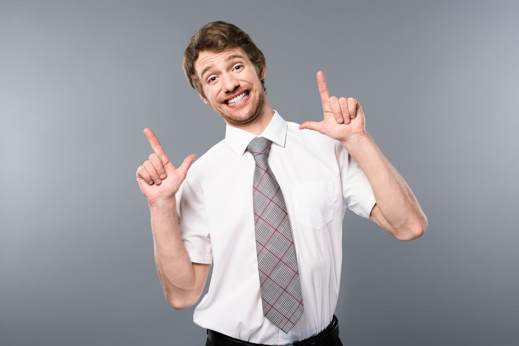 empresário positivo sorrindo e gesticulando em fundo cinza
 - Foto, Imagem