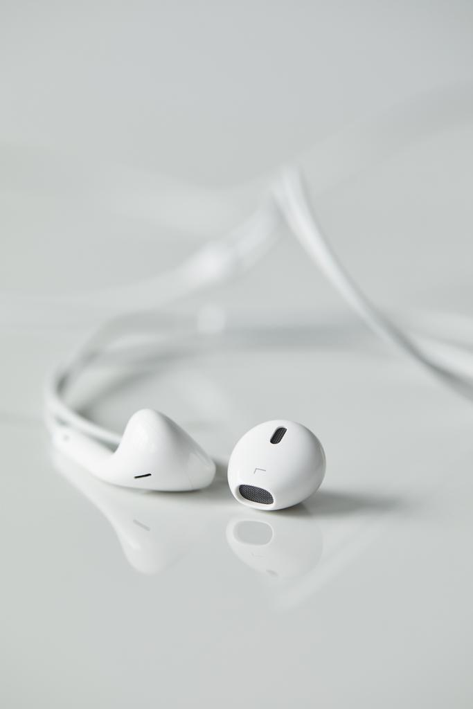 επιλεκτική εστίαση των λευκών ενσύρματων ακουστικών σε λευκή επιφάνεια με χώρο αντιγραφής - Φωτογραφία, εικόνα