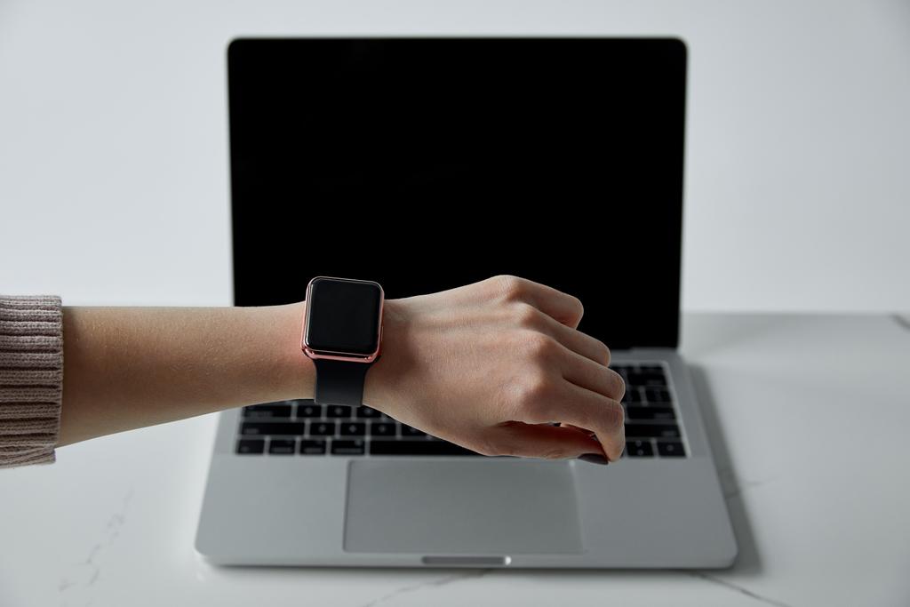 μερική θέα της γυναίκας σε έξυπνο ρολόι και φορητό υπολογιστή με κενή οθόνη απομονώνεται σε γκρι - Φωτογραφία, εικόνα