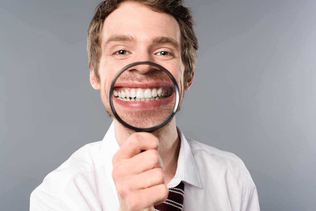 lachende zakenman met vergrootglas op grijze achtergrond - Foto, afbeelding