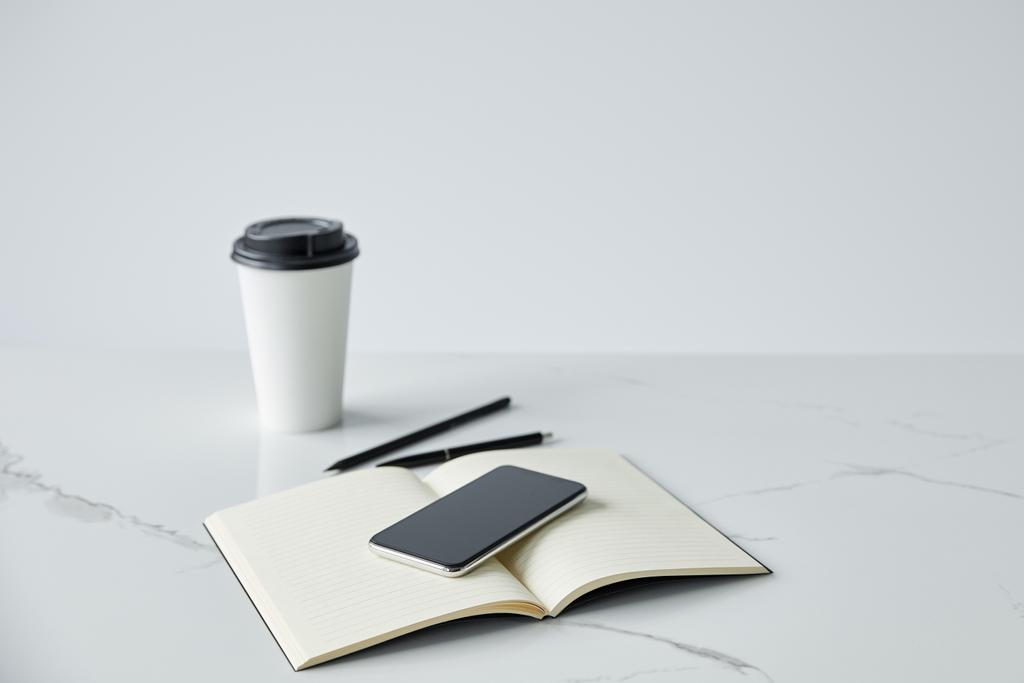 smartphone s prázdnou obrazovkou, notebookem a jednorázovým šálkem izolovaný na šedé - Fotografie, Obrázek