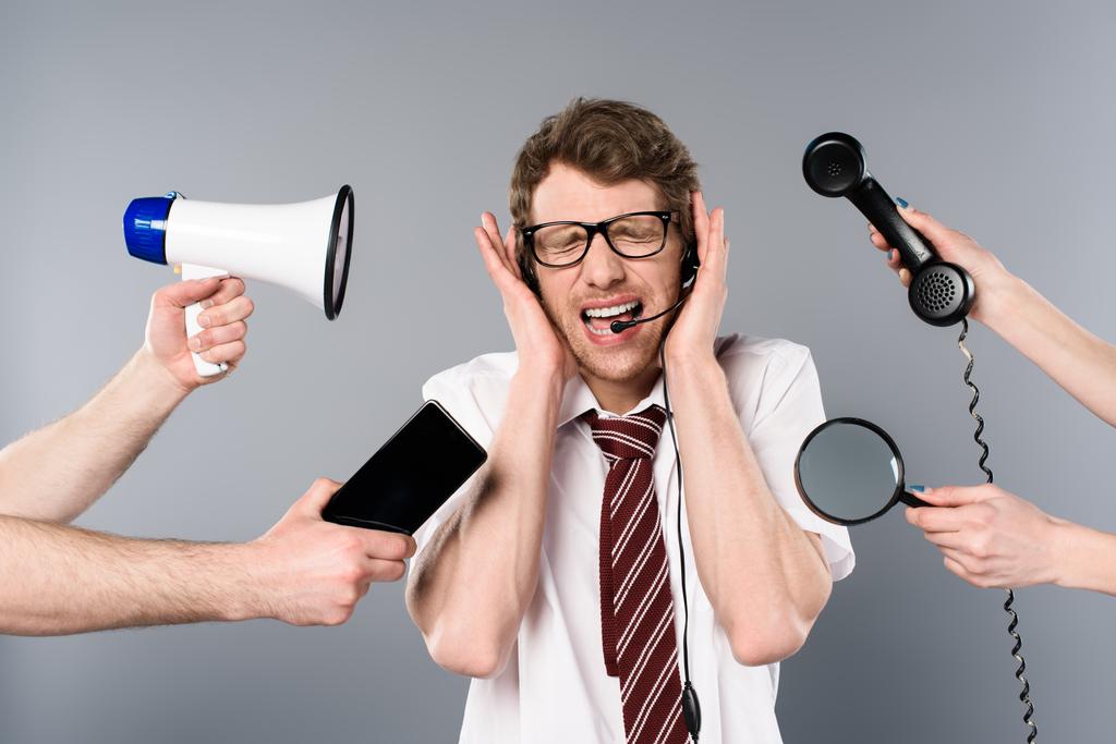operador de call center estressado em fone de ouvido gritando perto de megafone, smartphone, lupa e telefone
  - Foto, Imagem