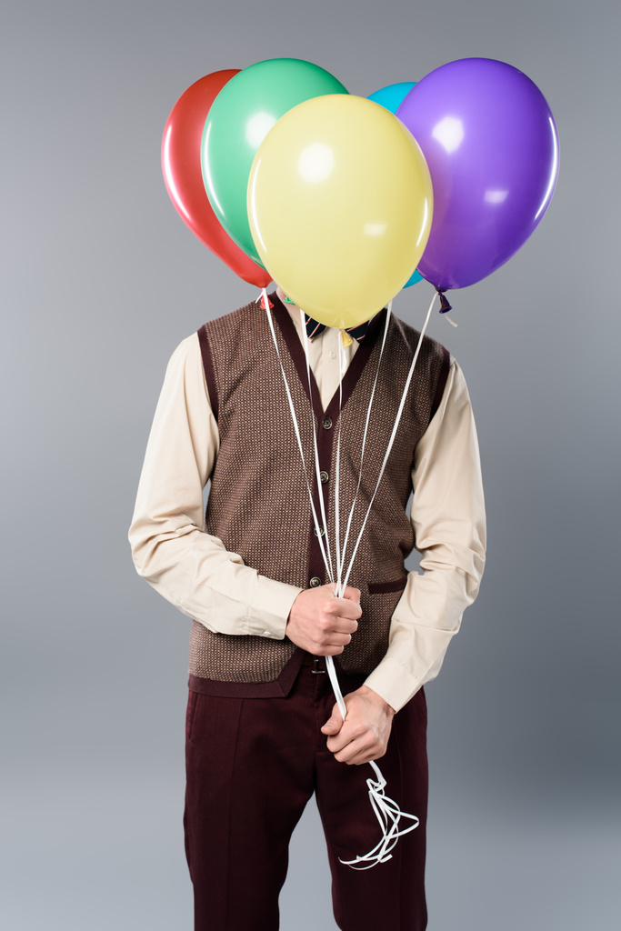 mies, jolla on hämärä kasvot tilalla monivärinen ilmapalloja harmaalla pohjalla
 - Valokuva, kuva