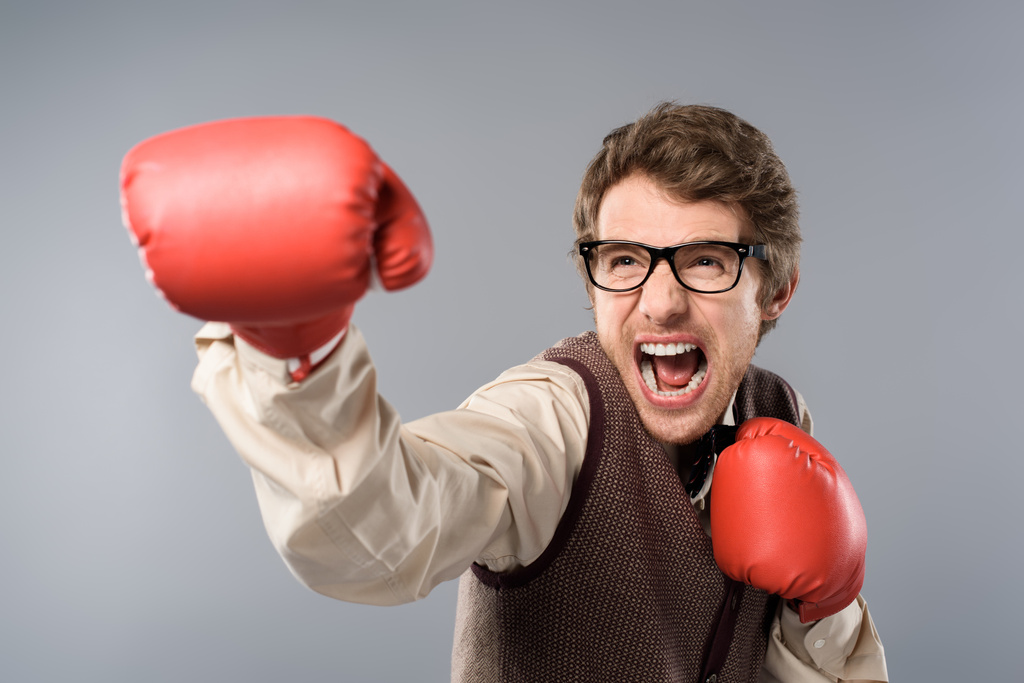 Wütender Mann mit Brille und Boxhandschuhen schreit vor grauem Hintergrund - Foto, Bild