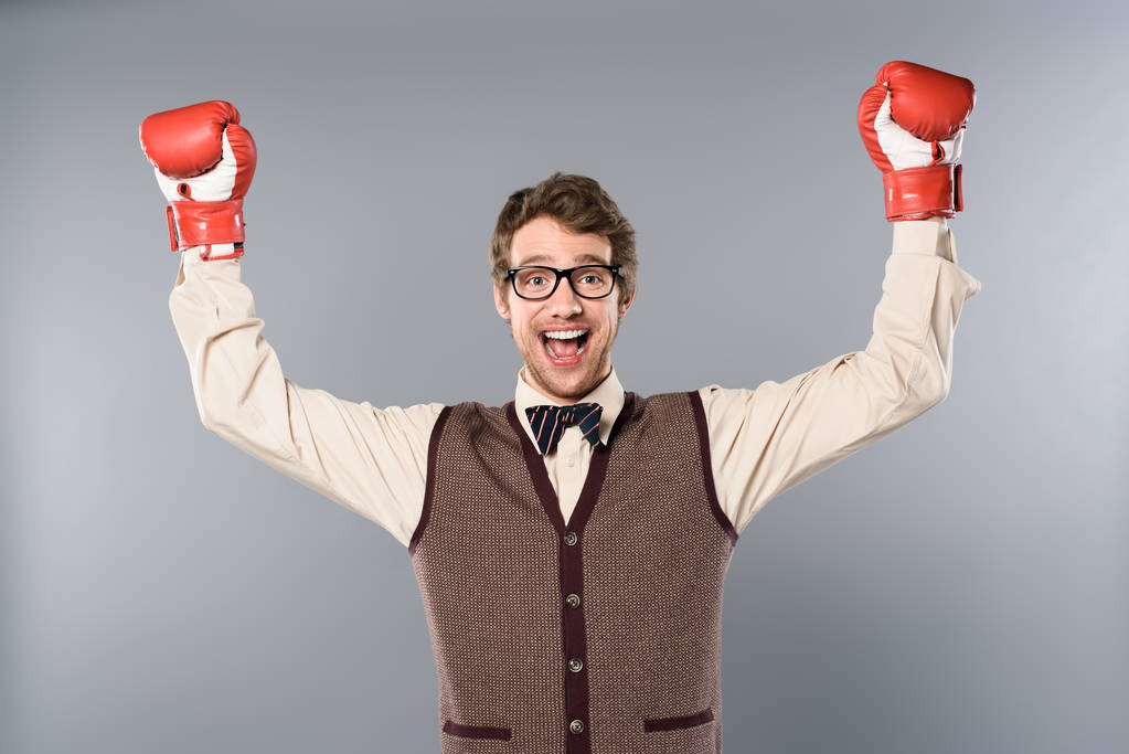 happy man in glasses and boxing gloves rejoicing on grey background - Photo, Image