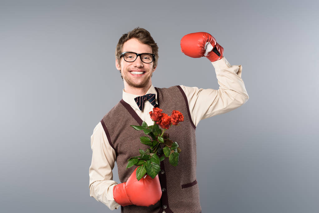 メガネと灰色の背景にバラの花束を持ってボクシング グローブで笑みを浮かべて男 - 写真・画像