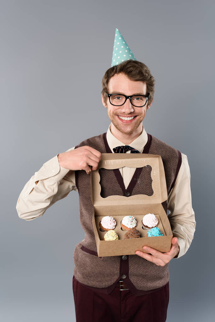 boldog mosolygó férfi szemüveg és fél kap gazdaság doboz cupcakes  - Fotó, kép