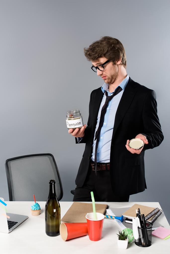 п'яний бізнесмен в окулярах дивиться на пенсійну коробку ізольовано на сірому
 - Фото, зображення
