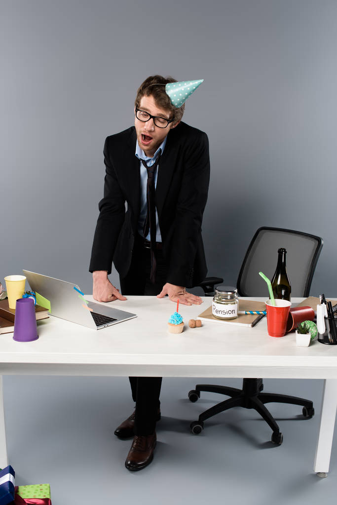 bâiller homme d'affaires dans la casquette de partie debout près du lieu de travail
  - Photo, image