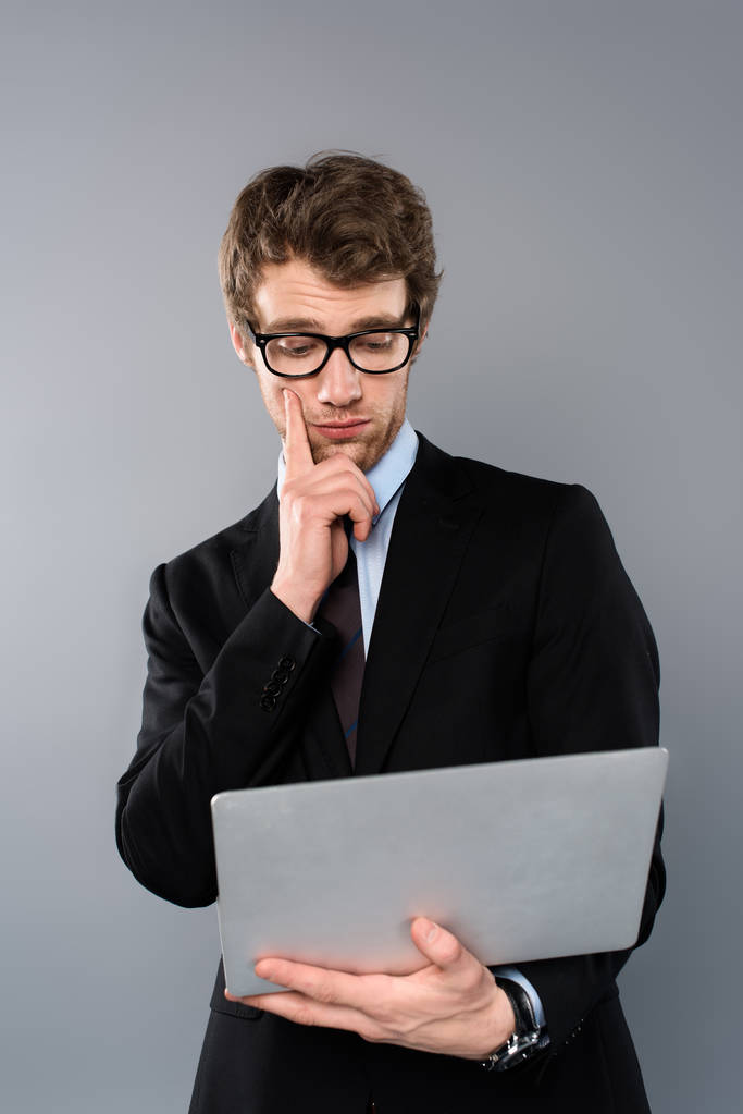 üzletember használ laptop elszigetelt szürke színben - Fotó, kép