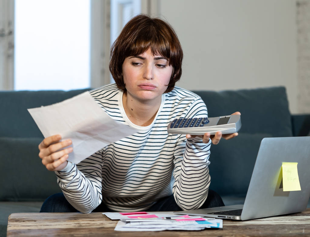 Worried and desperate young woman in stress accounting home or small business finances with too much debts and expenses. In online banking, paying bills mortgage and financial problems concept. - Photo, Image
