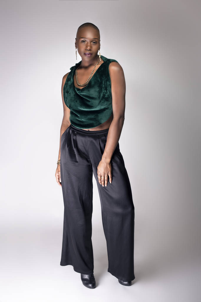 Modelo de moda femenina afroamericana negra posando con un peinado calvo de moda y ropa elegante en un estudio. Ella se ve confiada y mostrando una hermosa individualidad
. - Foto, Imagen