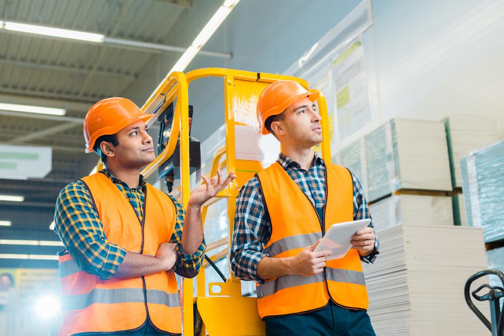 selective focus of multicultural workers looking away in warehouse - Photo, Image
