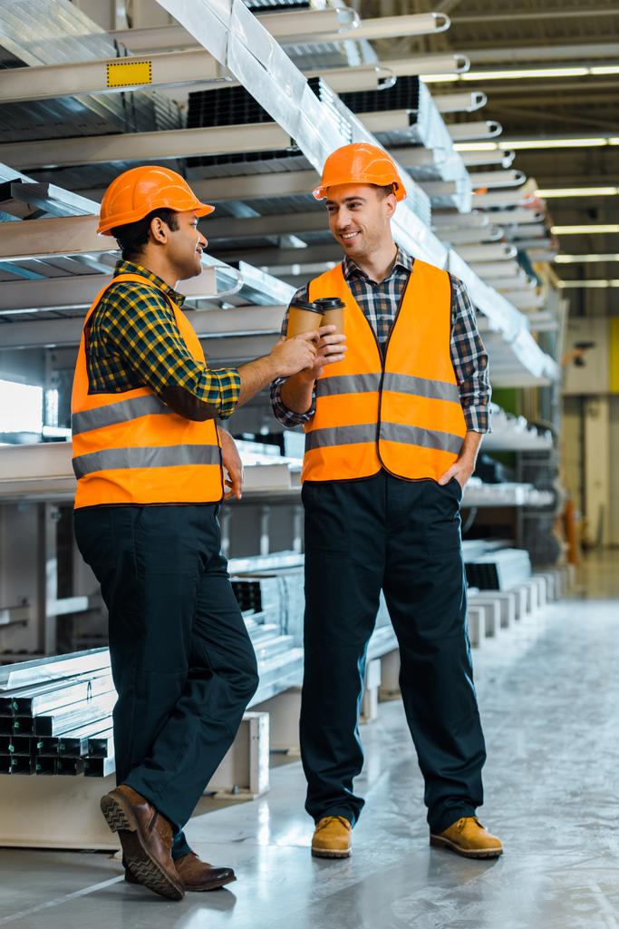 alegre multicultural trabajadores tintineo con papel tazas mientras de pie en almacén
 - Foto, Imagen
