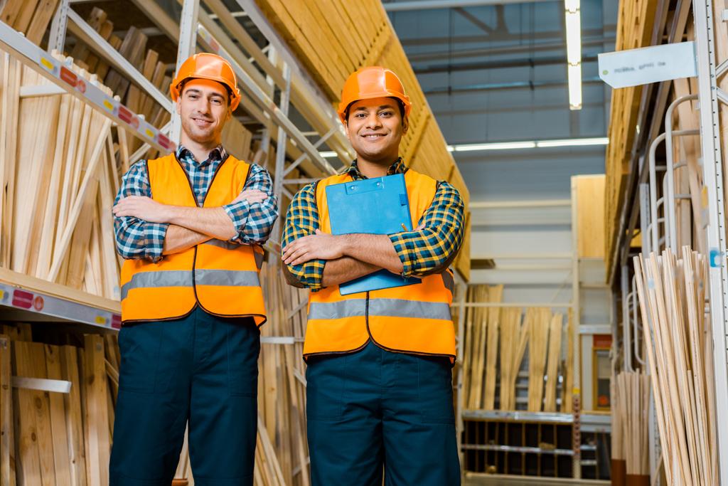 χαρούμενοι πολυπολιτισμικοί εργάτες με σταυρωτά χέρια χαμογελώντας και κοιτάζοντας την κάμερα - Φωτογραφία, εικόνα