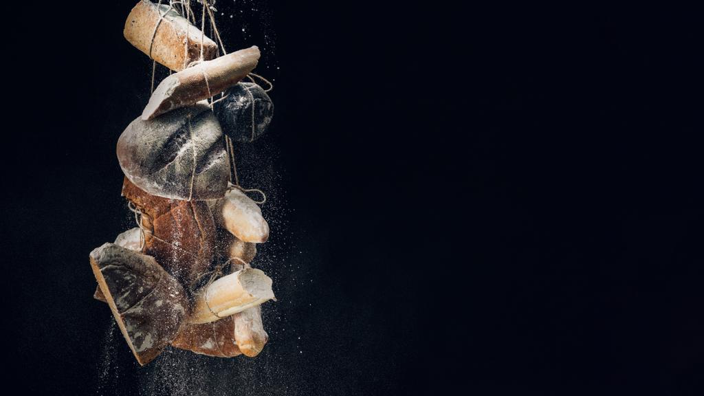 farinha branca caindo em pães, baguetes e croissant em cordas em fundo preto com espaço de cópia
 - Foto, Imagem