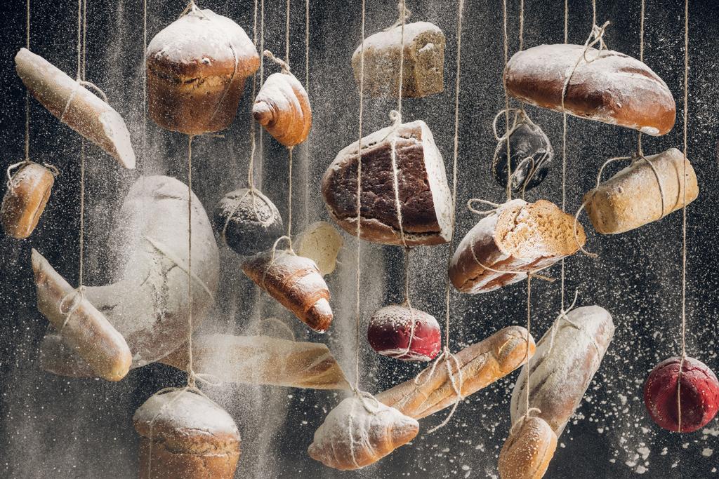 harina blanca cayendo en panes de pan blanco y marrón y pastelería colgando de cuerdas
  - Foto, imagen