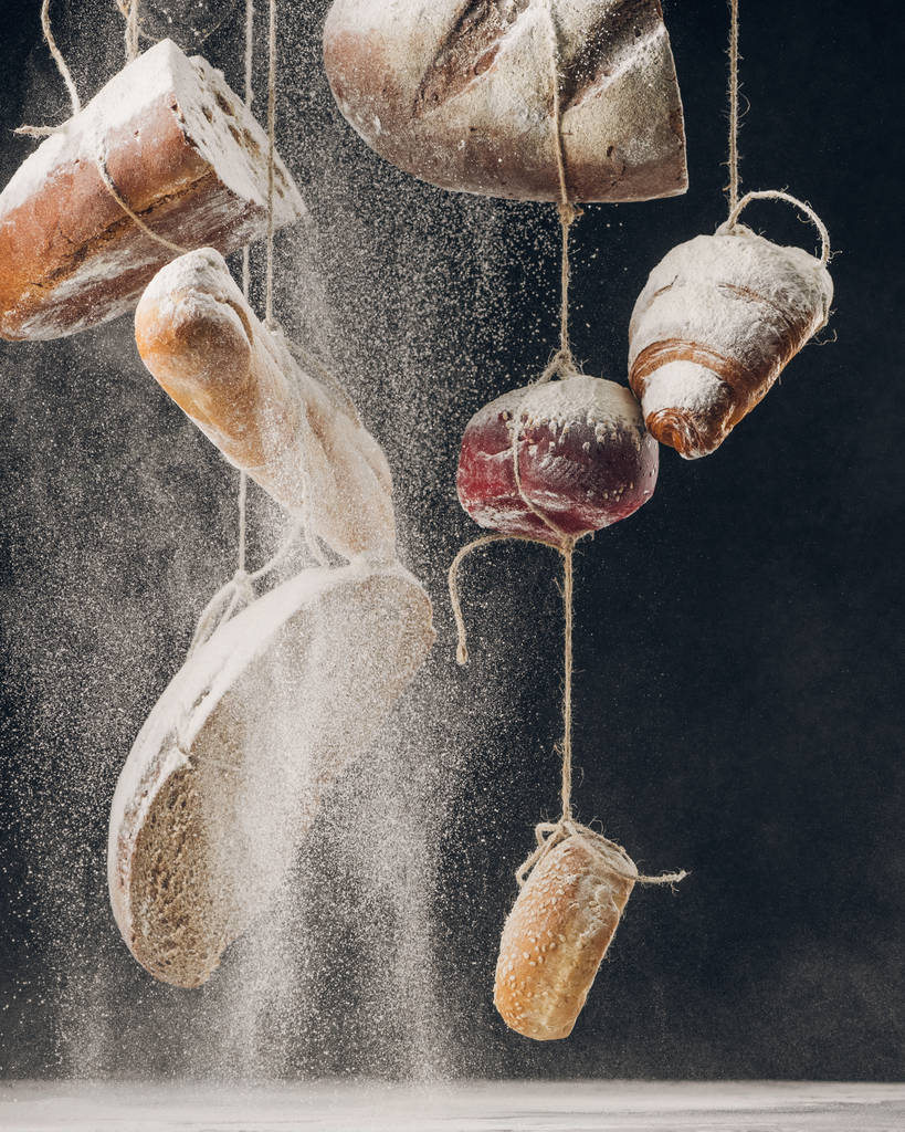 Mehl fällt auf selbstgebackenes Brot, das an Seilen hängt - Foto, Bild