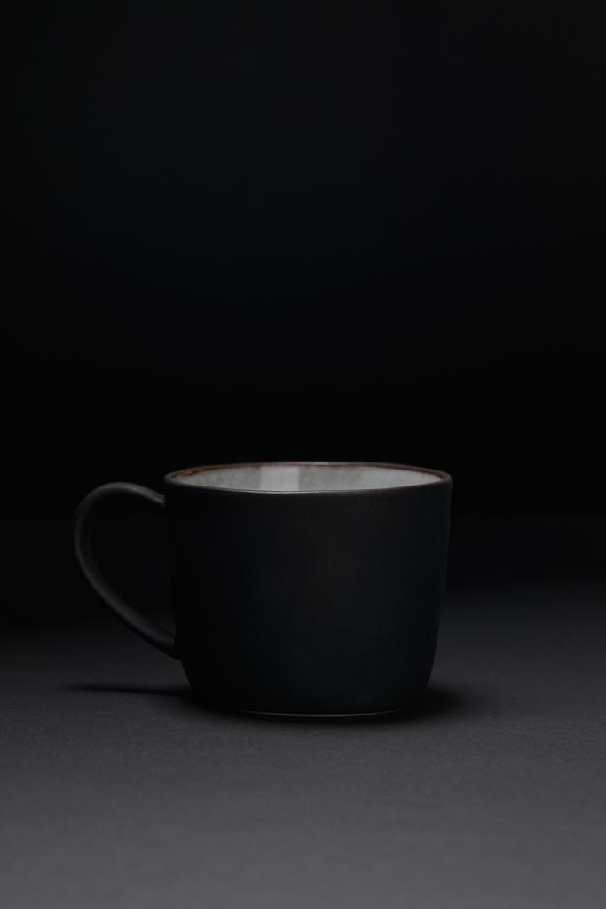 Кофейная чашка на темной текстурированной поверхности на черном
 - Фото, изображение