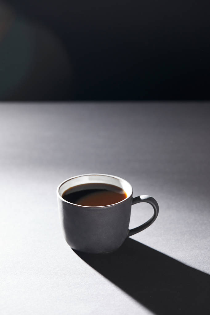 Kopje koffie op grijs oppervlak op zwart - Foto, afbeelding