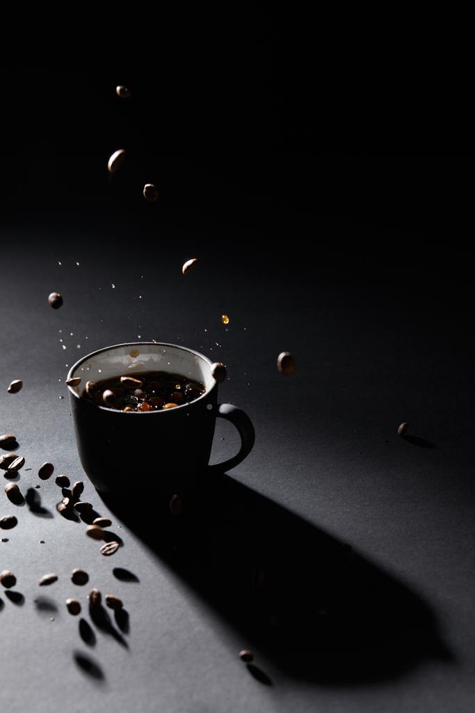 Tasse à café et grains de café sur surface texturée sombre
 - Photo, image