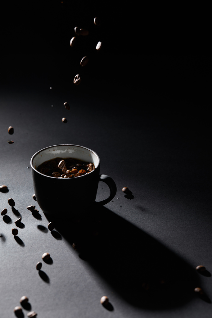 Φλιτζάνι καφέ και κόκκους καφέ σε σκούρα υφή επιφάνεια - Φωτογραφία, εικόνα