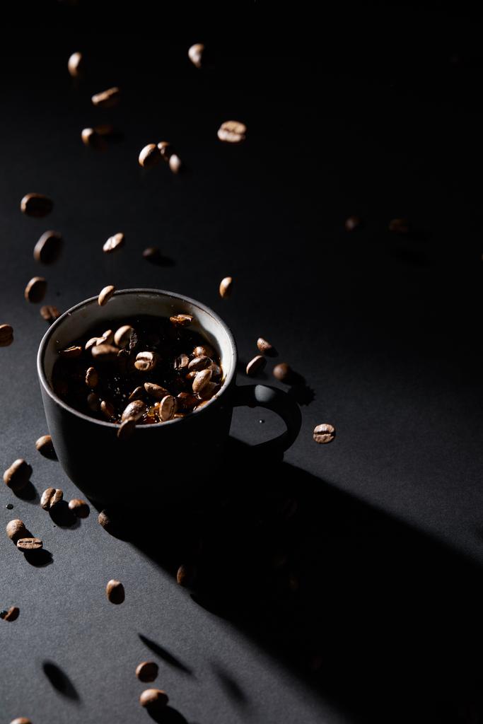 Koffiekopjes en koffie korrels op donkere textuur oppervlak - Foto, afbeelding