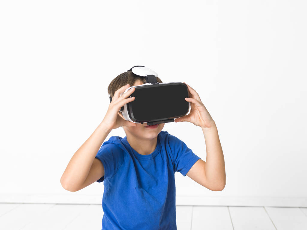 cool jongetje in rode broek en blauwe t-shirt met behulp van virtuele 3d bril thuis - Foto, afbeelding