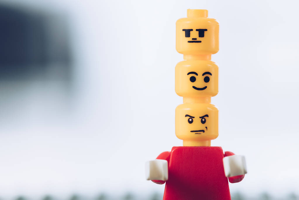 KYIV, UKRAINE - MARCH 15, 2019: red lego figurine with indifferent, smiley and angry faces on heads on white with copy space - Photo, Image