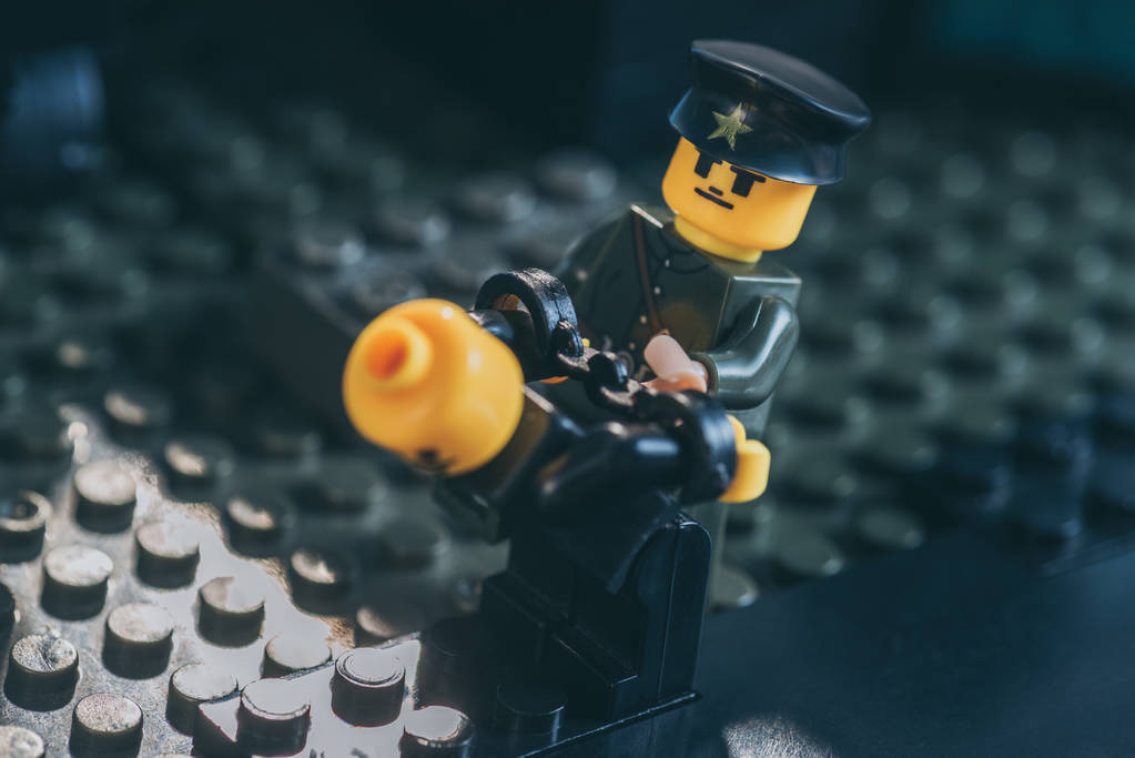 QUIIV, UCRÂNIA - MARÇO 15, 2019: policial figurino em uniforme e chapéu prendendo lego figura em preto
 - Foto, Imagem