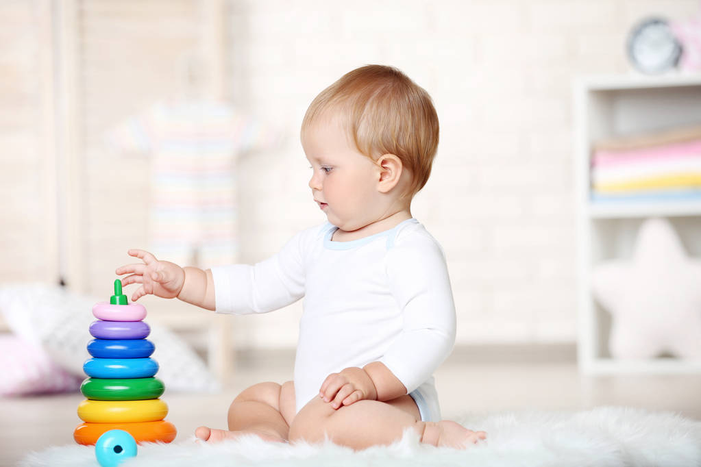 Bébé garçon avec des jouets assis sur le tapis à la maison
 - Photo, image