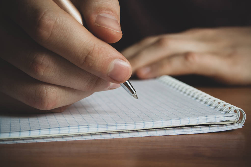 ένας άντρας με μια πέννα στο του χέρι γράφει σε ένα σημειωματάριο, κοντινό πλάνο - Φωτογραφία, εικόνα