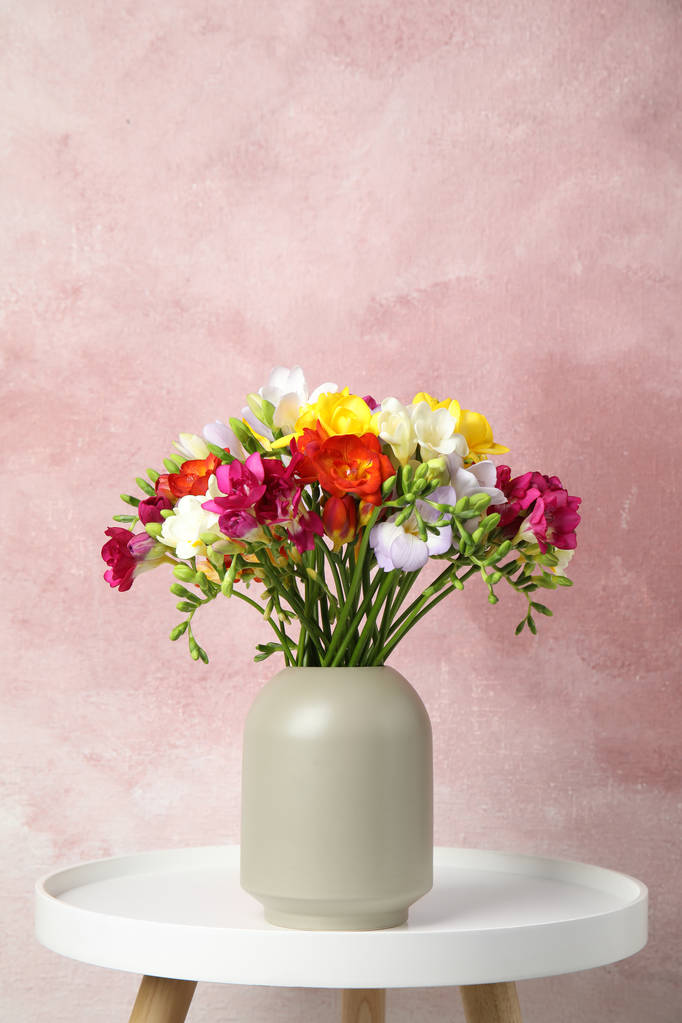 Ramo de flores de primavera freesia en jarrón sobre la mesa sobre fondo de color. Espacio para texto
 - Foto, Imagen