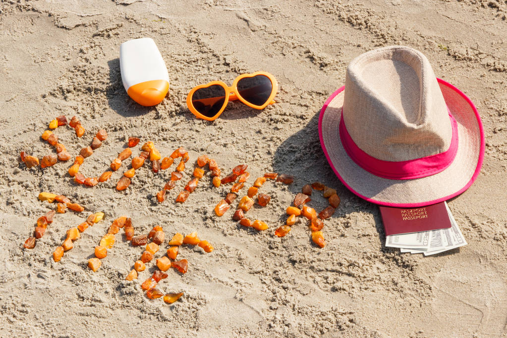 Inscription heure d'été, accessoires pour bronzer et passeport avec des devises dollar sur le sable à la plage
 - Photo, image