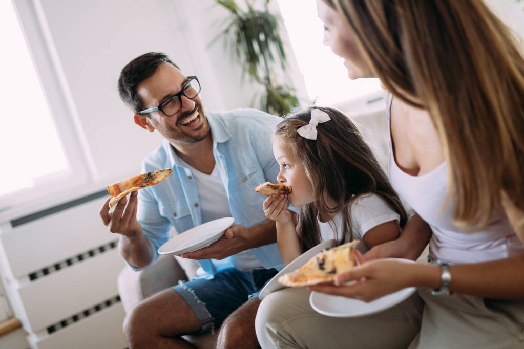 Retrato de família feliz compartilhando pizza juntos em casa
 - Foto, Imagem