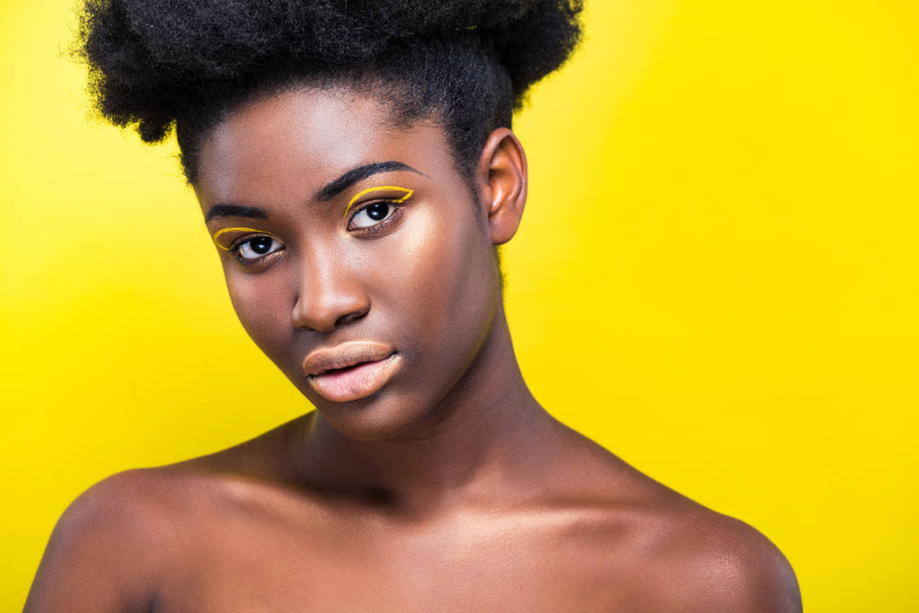 Houkutteleva afrikkalainen amerikkalainen nainen trendikäs meikki katsomalla kamera eristetty keltainen
 - Valokuva, kuva
