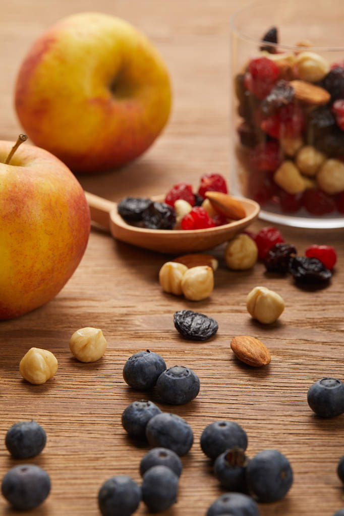 lähikuva mustikoita ja hasselpähkinöitä lähellä omenoita ja lusikka puinen pöytä
 - Valokuva, kuva