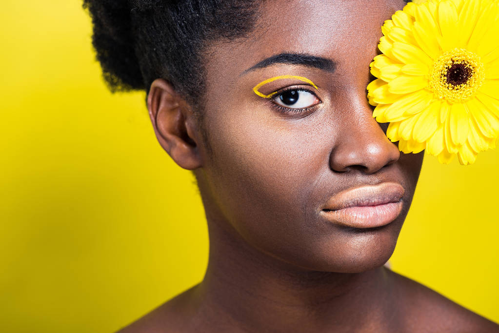 Sarı üzerinde kamera bakarak çiçek ile çarpıcı Afrikalı Amerikalı kadın  - Fotoğraf, Görsel