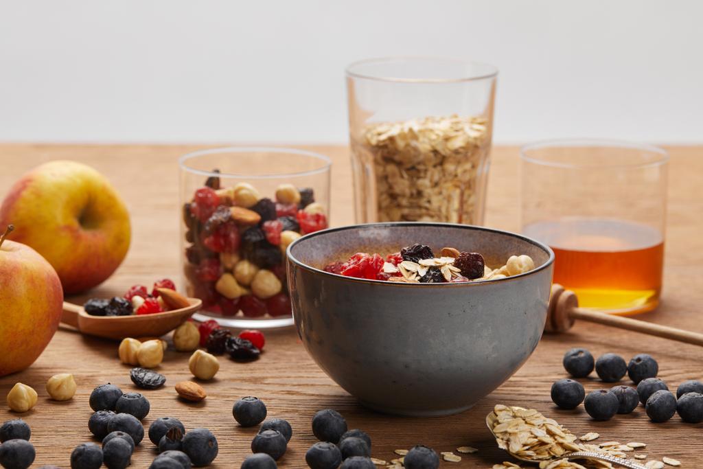 ягоди, горіхи і мюслі на сніданок на дерев'яному столі ізольовані на сірому
 - Фото, зображення