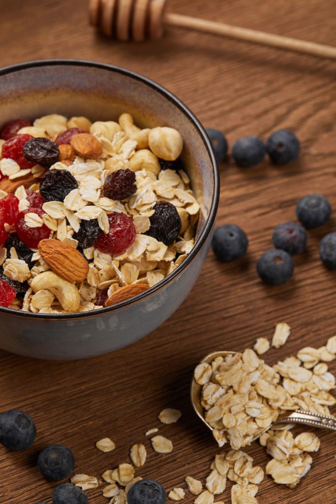 close up of berries, nuts and muesli in bowl for breakfast on wooden table - Photo, Image