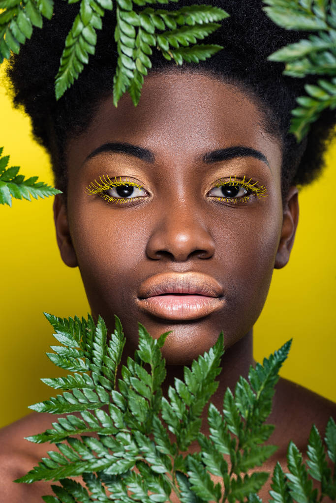 Vue de face de la belle femme afro-américaine avec fougère verte sur jaune
 - Photo, image