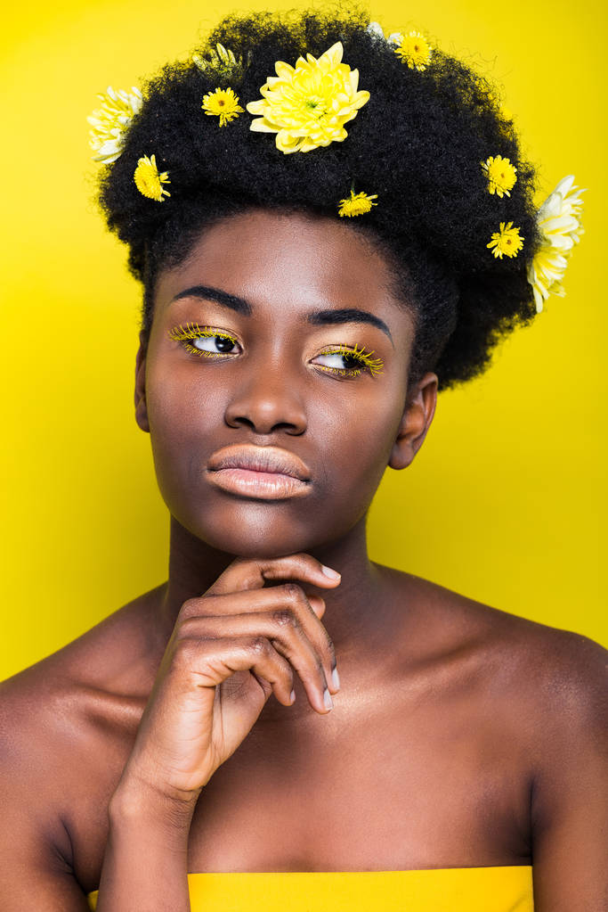 Страстная африканская американка с цветами в волосах, смотрящая на желтый
 - Фото, изображение