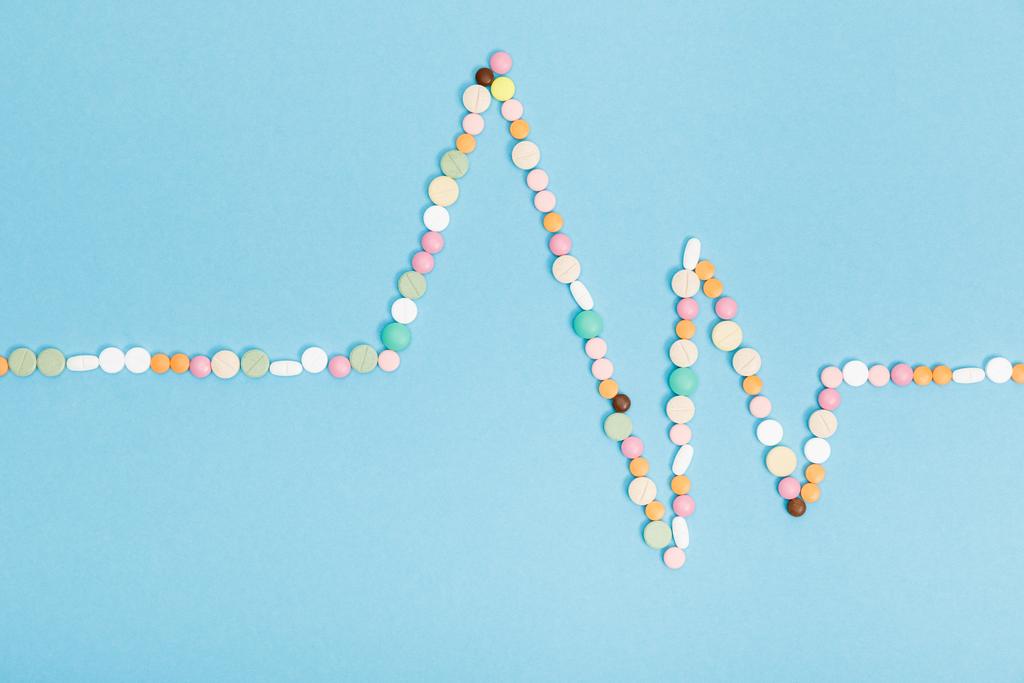 Płaski lay z kolorowymi tabletkami na niebieskiej powierzchni - Zdjęcie, obraz