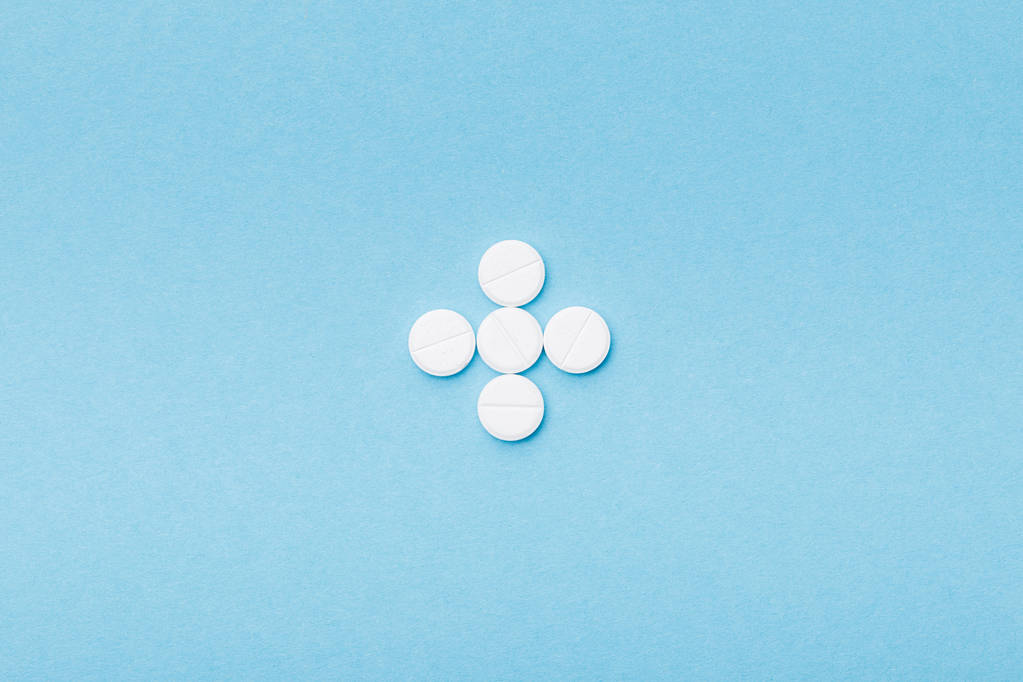 Pose plate avec des pilules blanches sur la surface bleue
 - Photo, image