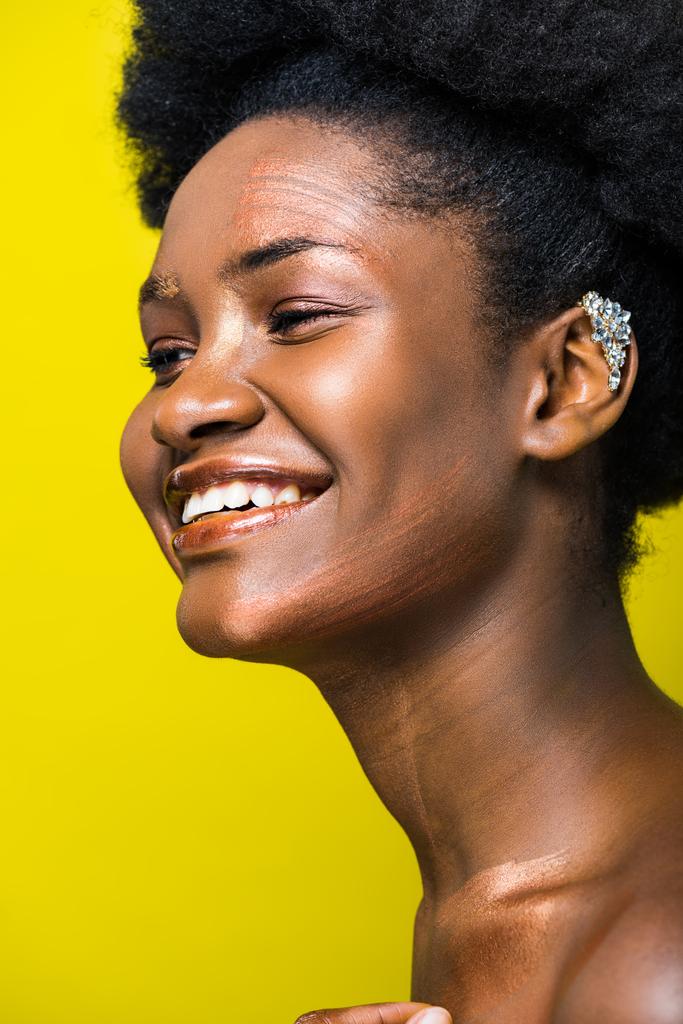 Γέλια αφρικανική Αμερικανίδα κορίτσι με το αυτί χειροπέδες απομονώνονται σε κίτρινο - Φωτογραφία, εικόνα