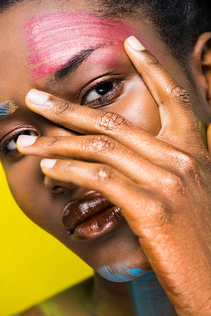 beautiful african woman with body art touching face with hand isolated on yellow - Photo, Image