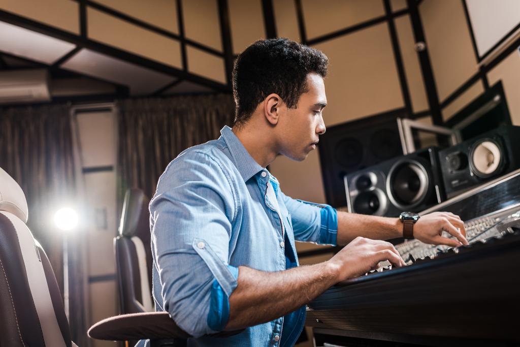 knappe mixed race muzikant werken bij Mixing Console in opnamestudio - Foto, afbeelding